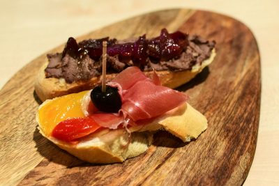 Pintxo Terina z kuracích pečienok s karamelizovanou cibuľou a tymiánom. Pintxo Šunka Serano s grilovanou paprikou a čiernou olivou